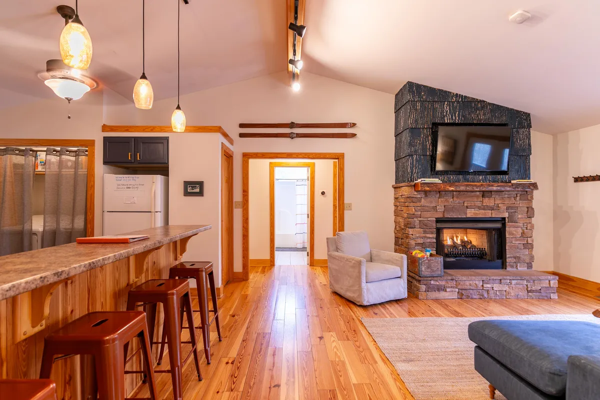 This interior image highlights a cozy living area with a gas fireplace, bar counter, comfortable seating, and a TV, all contributing to a warm and welcoming atmosphere—ideal for relaxing after outdoor winter activities.