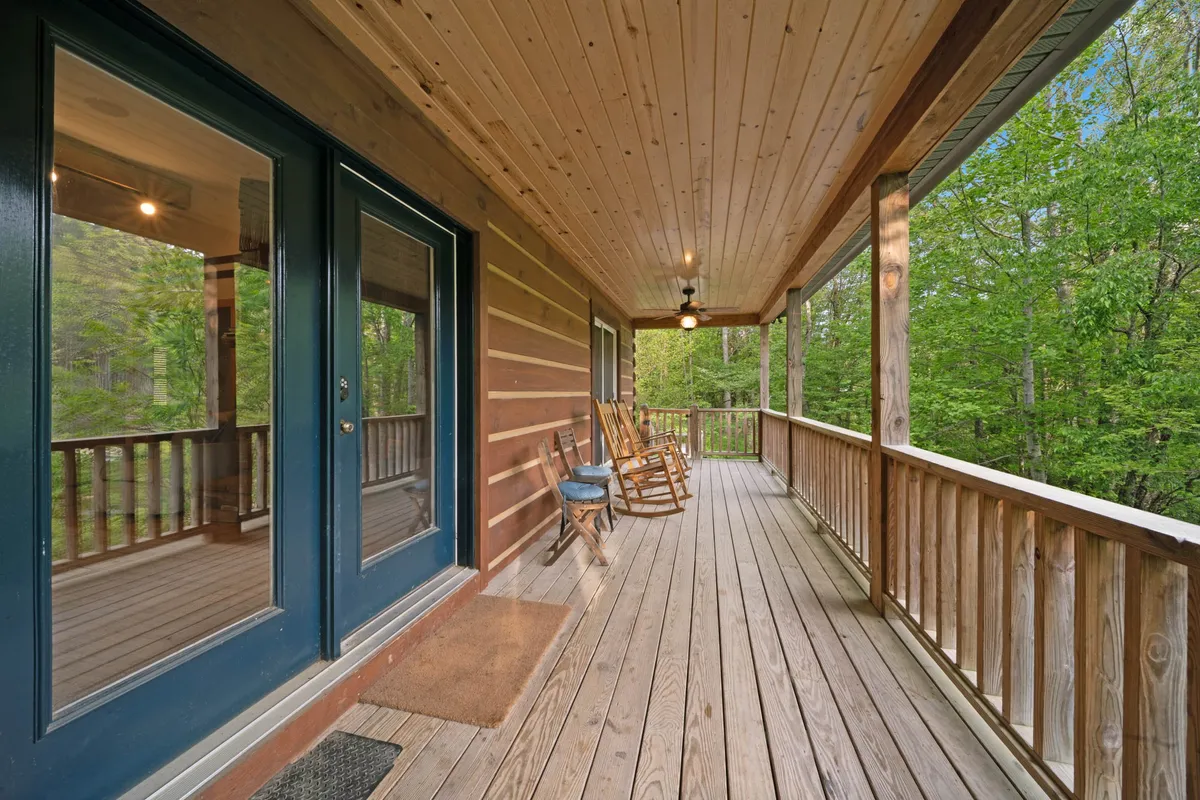 A spacious, inviting porch with wooden rocking chairs and a view of natural greenery. The porch setting is perfect for relaxing after a day of exploration, allowing both guests and their pups to unwind and soak in the fresh air and the sounds of the river.