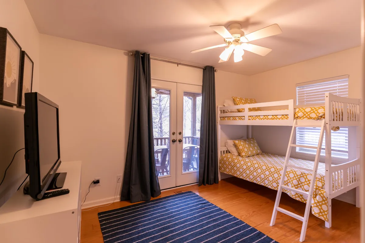 A bright, family-friendly room with a bunk bed, TV, and double doors leading out. The space feels ideal for groups or families with pets, with easy access to the outdoors.