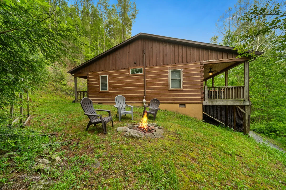 This image captures the inviting outdoor fire pit area, surrounded by comfortable seating and set against the backdrop of the cabin exterior. The warm glow of the fire creates a cozy atmosphere, perfect for gathering with friends or family after a day of winter adventures.