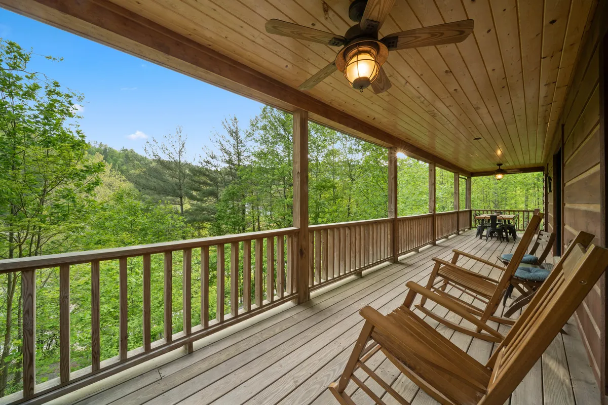 The hero image showcases the inviting front porch of the Watauga River Retreat cabin, featuring classic wooden rocking chairs and a rustic dining table set against a backdrop of lush greenery. The porch is bathed in soft morning light, suggesting tranquil sunrise views and the promise of peaceful evenings surrounded by nature. The setting conveys a sense of relaxation, connection, and the simple pleasures of mountain living.